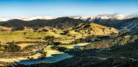 The stunning Tararua Ranges and the river meandering through the valley with a light covering of cloud on peaksの写真素材