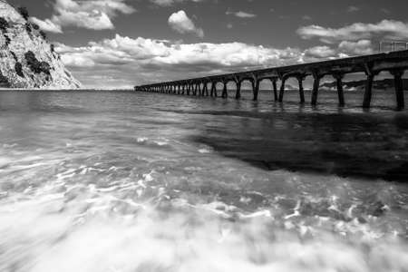 Moody monochrome long exposure of Tokomaru Bay pier on a cloudy day
