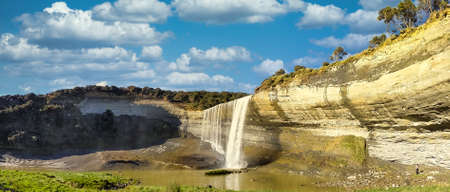 The person  in the bottom right demonstrates the scale and size of the huge Mangatiti Falls in rural farmlandの写真素材