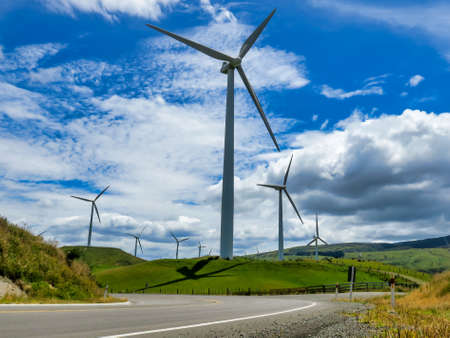 Modern concrete Wind farm and turbines generating electricity in nature's vibrant lush grazing fields on the agricultural farmlandsの写真素材