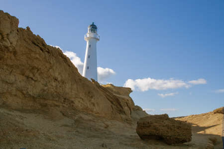 Landmark CastlePoint lighthouse viewed from the rocky landscape on a sunny and cloudy dayの写真素材