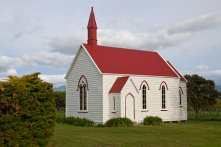 Cute quaint old weatherboard chapel with red roof and spire in rural countrysideの写真素材