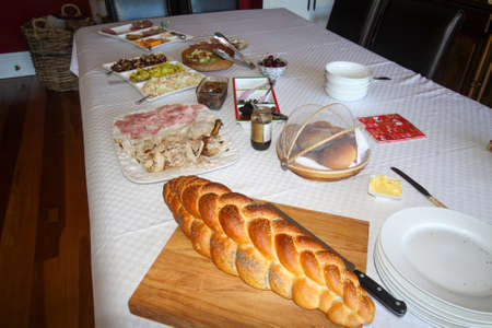 Freshly backed cob of bread and assorted col meats and pickles on the dining room tableの写真素材