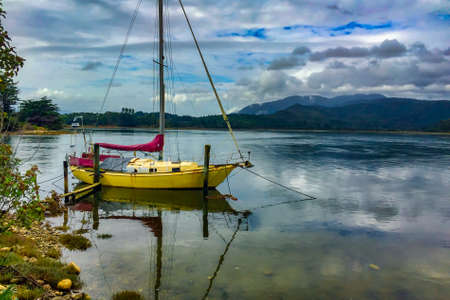 Beautiful yellow yacht moored by the shore ready for sailingの写真素材