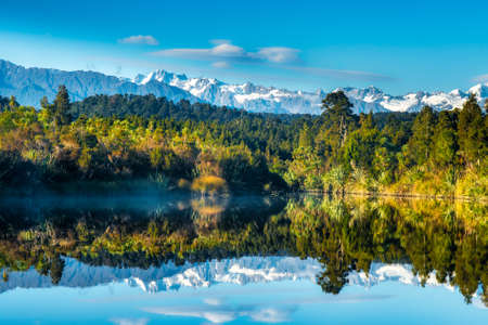 Mirror image reflections of the snow capped Southern Alps on Okarito Lagoon on the West Coastの写真素材