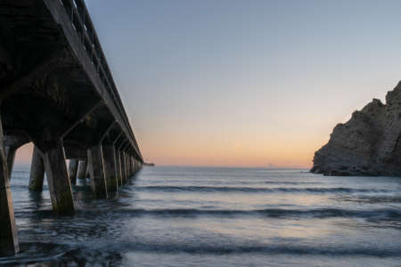 Before dawn with the sky lighting up in the gap between the wharf and the cliffの写真素材