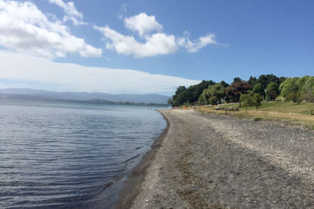 Deserted pristine new zealand beach lined with hills and forestの写真素材