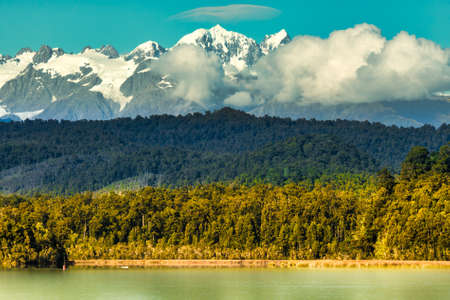 Layers of nature water trees forest and snow covered Southern Alps of New Zealandの写真素材