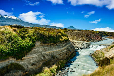 Stream running through the desert road with twin volcanos in the backgroundの写真素材