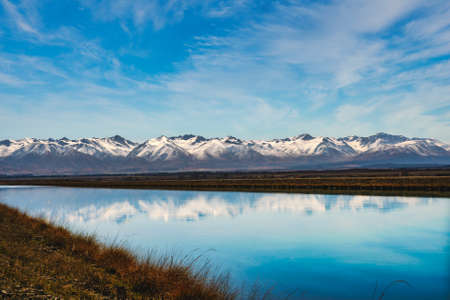 Snow covered Southern Alps mountain range near Twizel reflected in the still water in the canal...