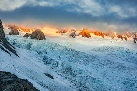 The sun bursting through the thick cloud at the top of the glacier in the Southern Alp peaksの写真素材