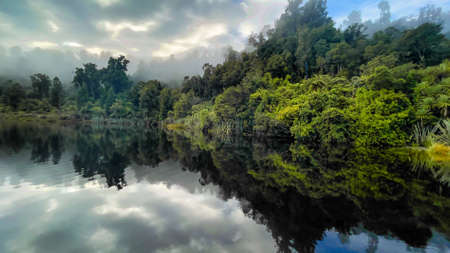 Misty lake Mapourika reflections on the still water in the early morning low cloud and fogの写真素材