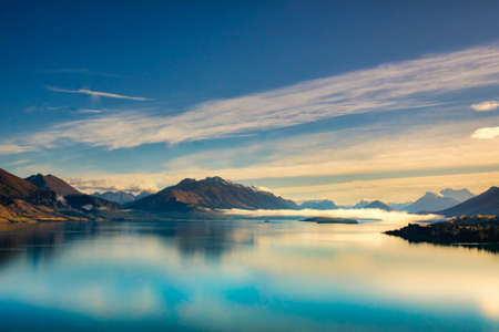 Stunning panoramic view of the Southern Alps  and the mountain reflections on the very calm still water of Lake Wakatipuの写真素材