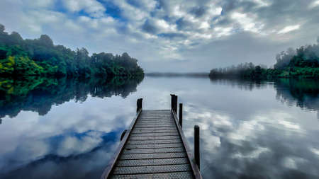 Lake Mapourika on the South Island West Coast with its jetty shrouded in in mist and low cloud in the early morningの写真素材