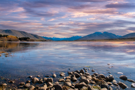 Stunning  cloudscape colours and reflections over Lake Clearwater with a rock lakeshore in the foregroundの写真素材