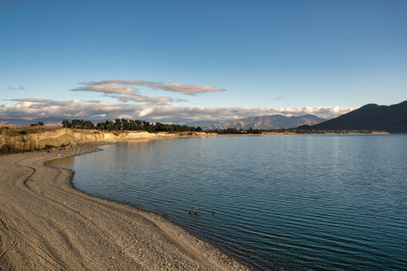 Rugged tall mountain range and lake side scenery around the shores of alpine Lake Hawea