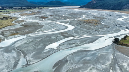 Aerial drone scenery of the braided Dart river flowing through a rural valley bordered by the Southern Alps mountains into Lake Wakatipu near Glenorchyの写真素材