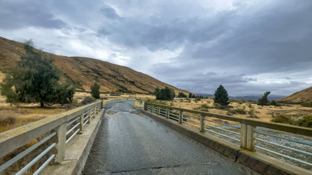 Flooded stream on the winding narrow gravel road between Lake Tekapo and Lake Pukaki in rural agricultural landの写真素材