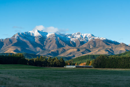 Agricultural farm fields and out building beneath snow capped mountains