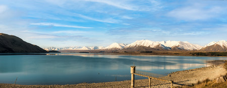Beautiful wispy cloudscape over the mountain ranges and water of Lake Tekapoの写真素材
