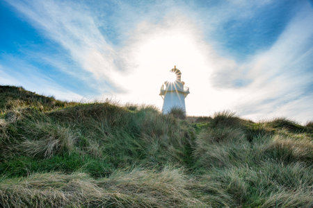 The iconic Waipapa Point Lighthouse emerging above the tussock covered sand dune on the south west coast of the South Island NZの写真素材