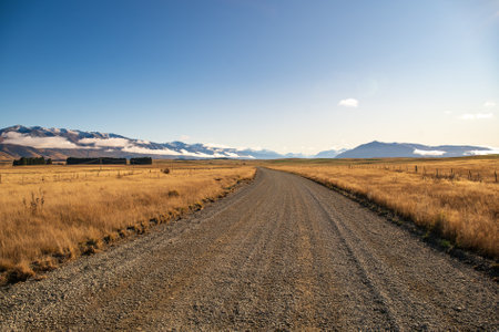 Gravel road in New Zealand with snow capped mountains in the backgroundの写真素材