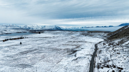Winter landscape with snow covered meadow and forest in a cloudy dayの写真素材