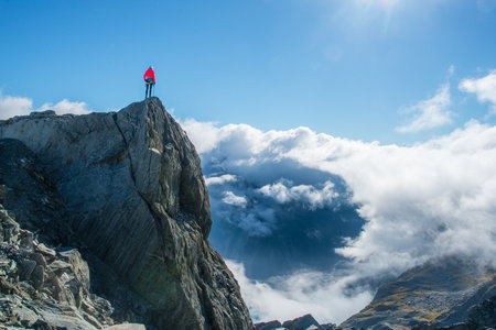 Man standing on top of a mountain and enjoying the view of the cloudsの写真素材