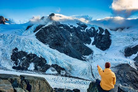 Woman in yellow jacket on the background of snow-capped mountainsの写真素材