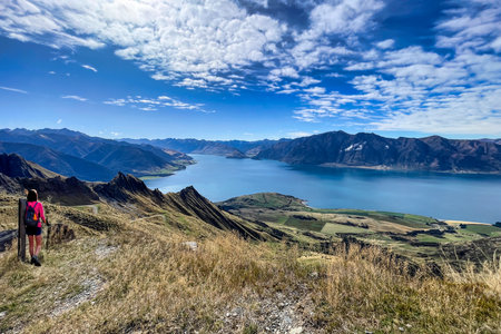 Rear view of hiker enjoying the  views of lake Hawea from the Isthmus track walkway whilst making a heart symbolの写真素材