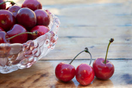Ripe cherries in a glass vase. Cherries on a wooden table. High quality photo