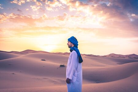 Berber man wearing traditional tuareg clothes in the Sahara Desert at dawn, Merzouga, Moroccoの写真素材