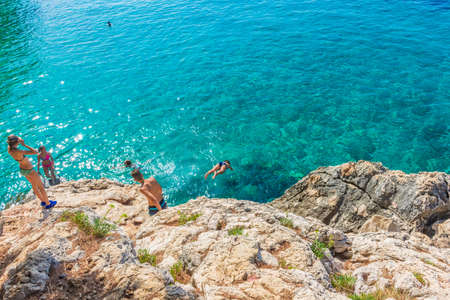 HVAR, CROATIA, AUGUST 8 2019: A tourists family diving into the beautiful and crystal water of...