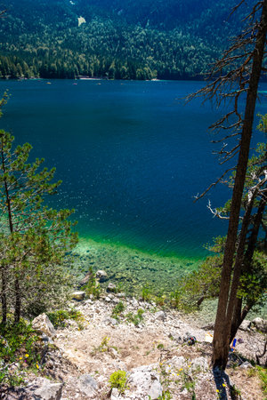 Faboulus landscape of Eibsee Lake with turquoise water in front of Zugspitze summit under sunlight....
