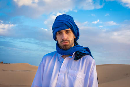Young arabic man wearing traditional berber clothes in the Sahara Desert of Merzouga, Moroccoの写真素材