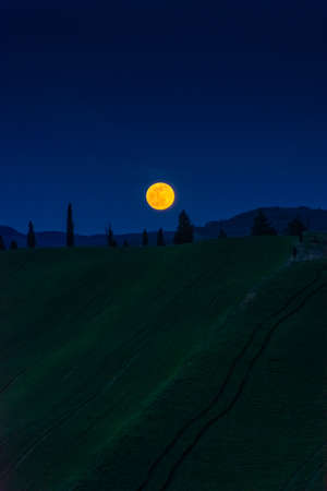 A beautiful full moon over the countryside of Tuscany, Italyの写真素材