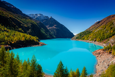 Autumnal landscape of the Lake Place Moulin, an artificial glacial lake with turquoise water in the italian Alps, on the border with Switzerlandの写真素材