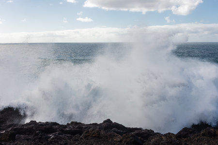 Powerful waves of the Atlantic Ocean crashing on the volcanic cliffs of Los Hervideros in Lanzarote,...
