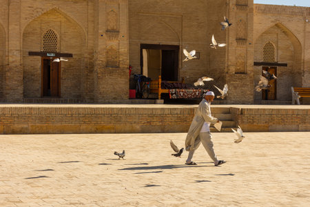 Bukhara, Uzbekistan, 16 August 2023:Imam of the Chor Bakr Necropolis feeding his pidgeonsの写真素材