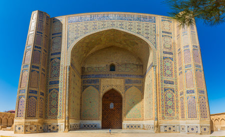 Samarkand, Uzbekistan, 15 August 2024:Kid in front of the giant gate of Bibi-Khanym Mosqueの写真素材