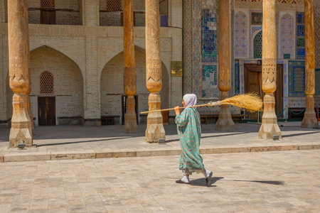 Bukhara, Uzbekistan, 16 August 2023:Uzbek woman carrying a broomの写真素材