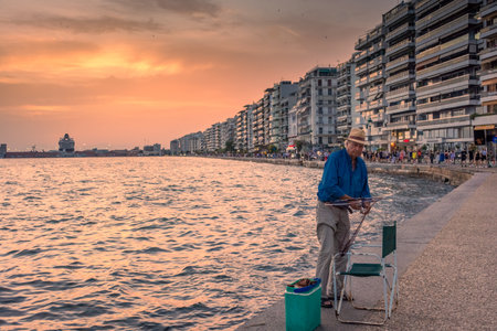 Thessaloniki, Greece, 13 June 2024: Fisherman on the promenade at sunsetの写真素材