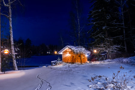 Lonely wooden cabin on the shore of a frozen lake. Snowy landscape at night in LempÃ¤Ã¤lÃ¤, Finlandの写真素材