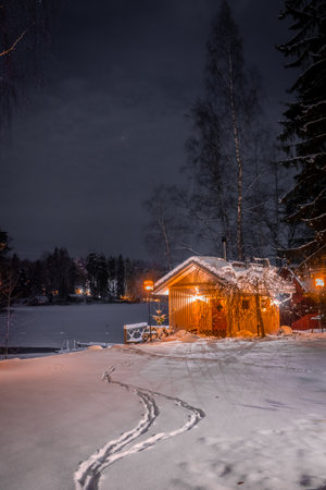 Lonely wooden cabin on the shore of a frozen lake. Snowy landscape at night in LempÃ¤Ã¤lÃ¤, Finlandの写真素材