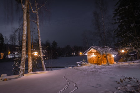 Lonely wooden cabin on the shore of a frozen lake. Snowy landscape at night in LempÃ¤Ã¤lÃ¤, Finlandの写真素材