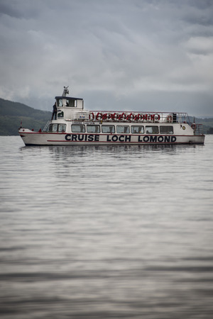 Scotland, UK - 2013, August, 7 - A boat leaving the quay for a cruise in Loch Lomondのeditorial素材