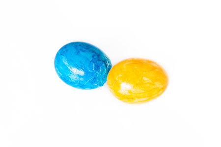 Eggs peck with blue and yellow Easter eggs and white backgroundの写真素材