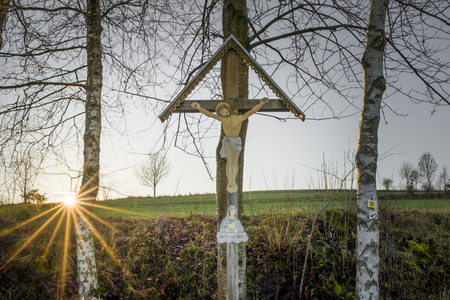 Sunset and last sunbeams with a way cross in the Bavarian forestの写真素材