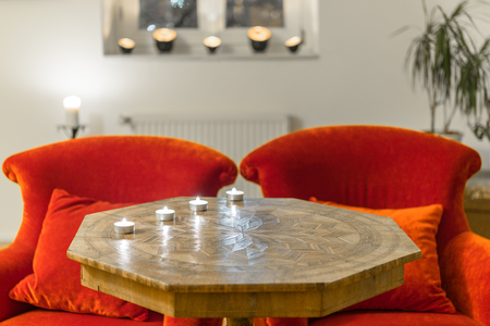 Candles on a antique side table with intarsia and red chairの写真素材