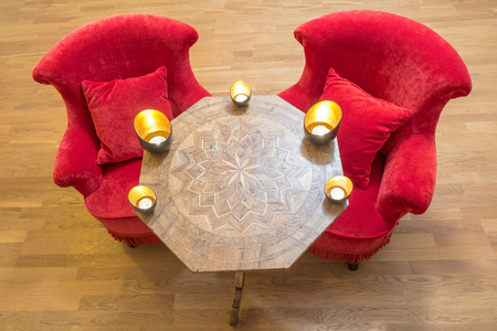 Candles on a antique side table with intarsia and red chairの写真素材